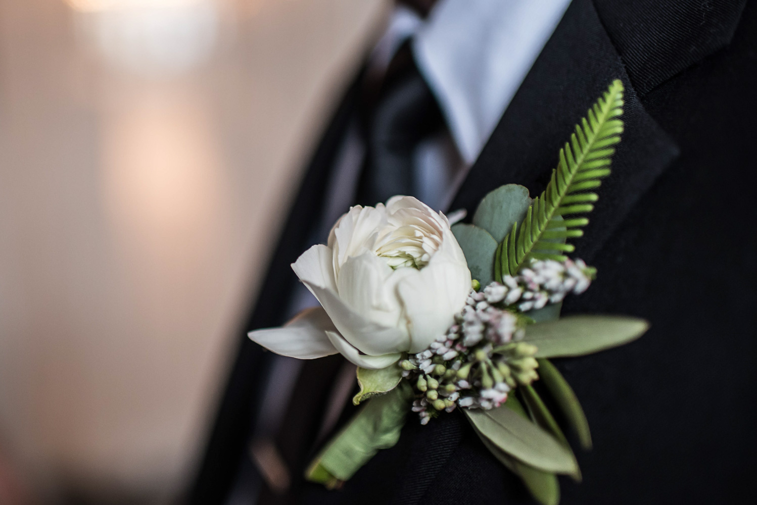 white boutonniere pinned on the groom's tuxedo at Aria in Minneapolis