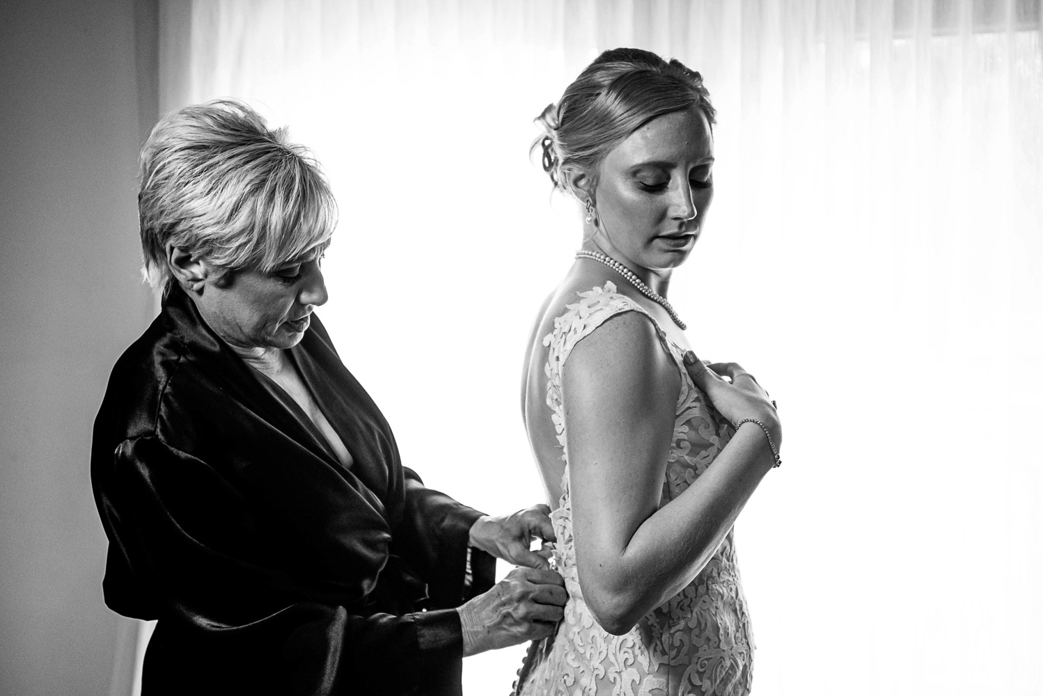 mom helping bride put on her dress before her summer wedding in Minnesota