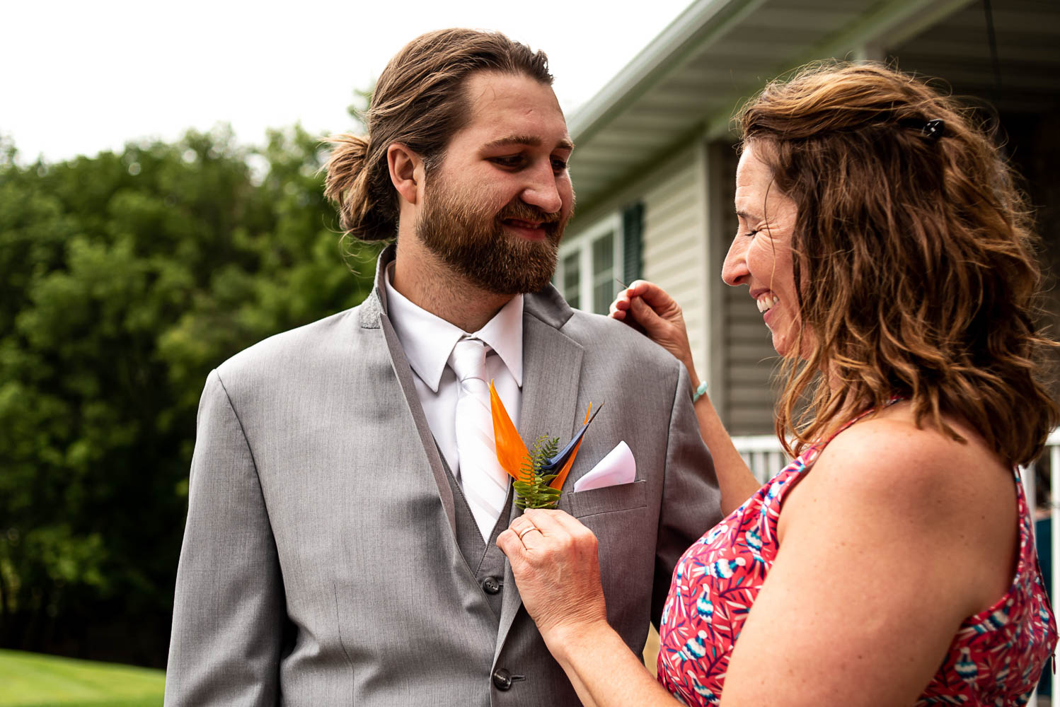 groom's mom pinning on his boutonniere before his summer wedding ceremony