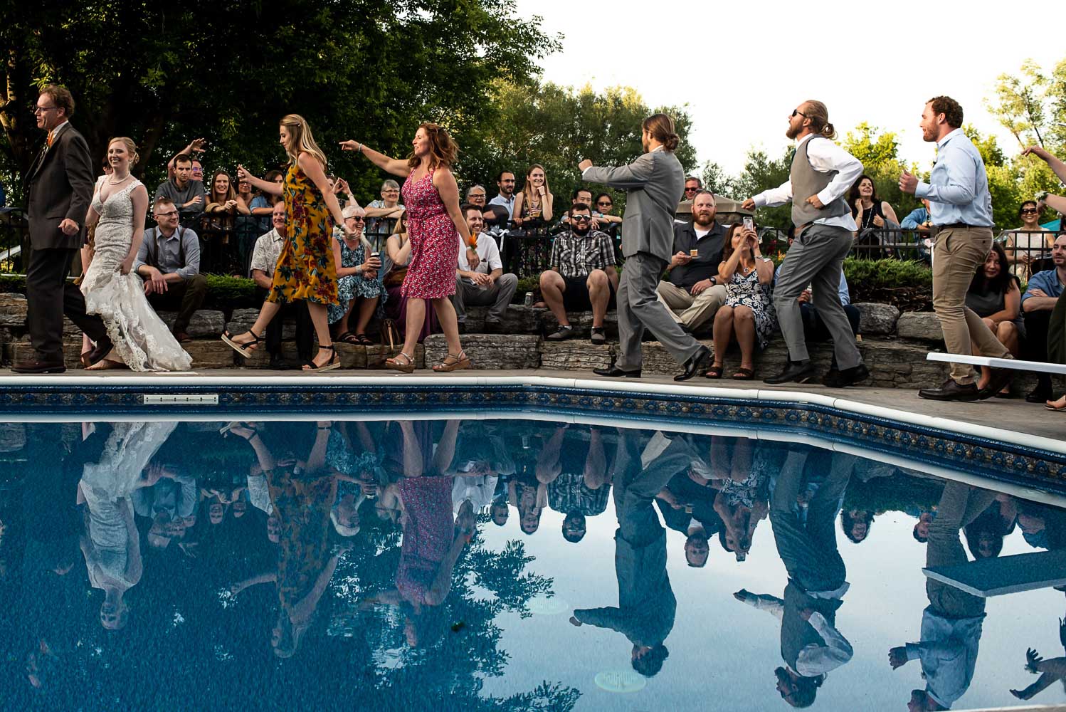 wedding guests doing the conga around a swimming pool during a Minnesota wedding