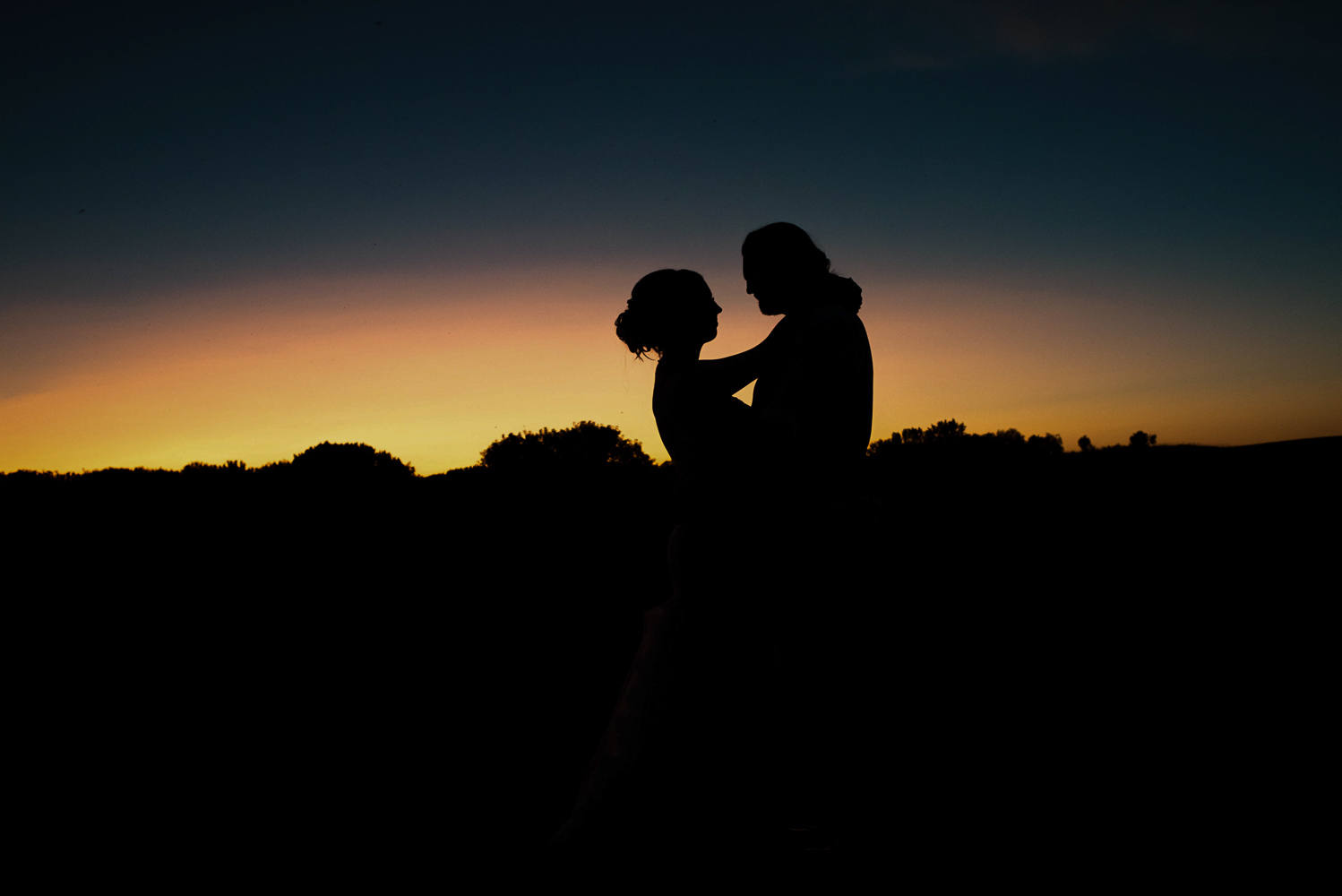 bride and groom silhouetted in the sunset at the end of the wedding day
