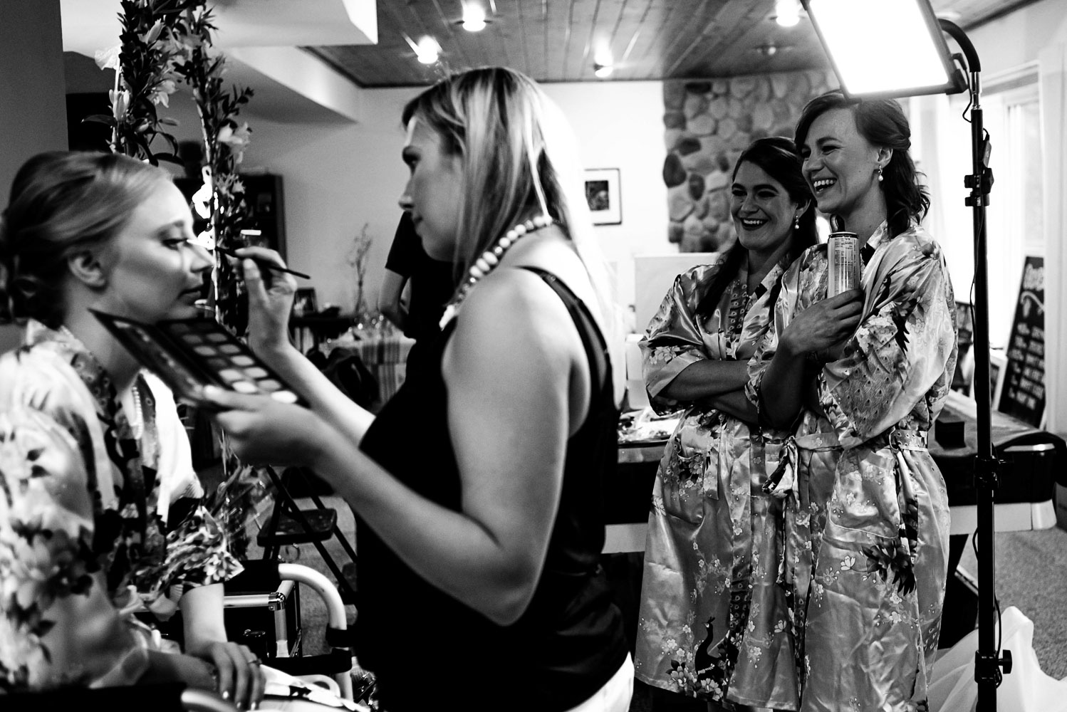 bridesmaids watching the bride get her makeup on before her summer backyard wedding in Minnesota