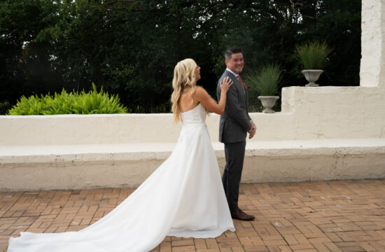 Bride rests hand on grooms shoulder as he smiles prior to seeing her for the first time before wedding ceremony,