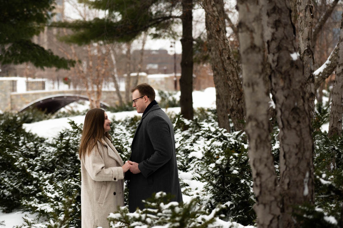 A couple holding hands in a park lightly covered in snow