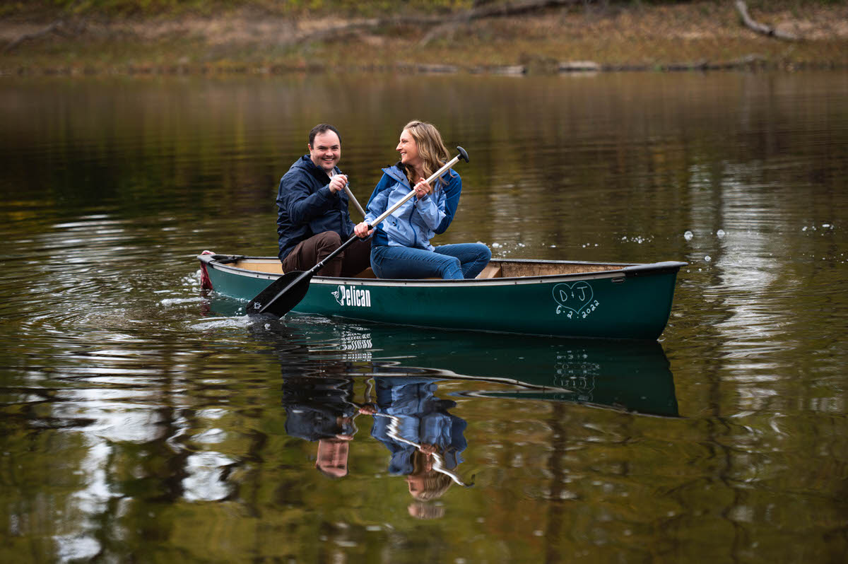 A couple laughing together as they paddle a canoe
