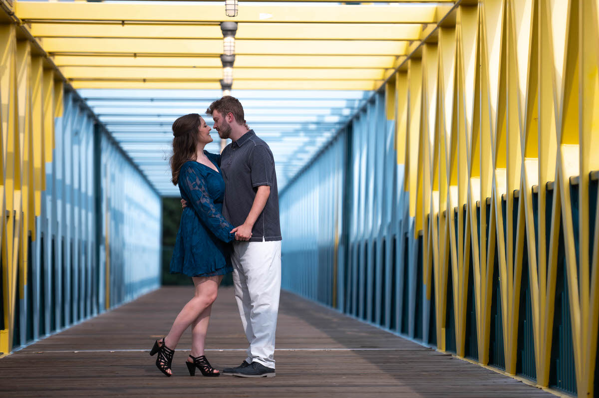 A couple holding hands together on a bridge about to kiss