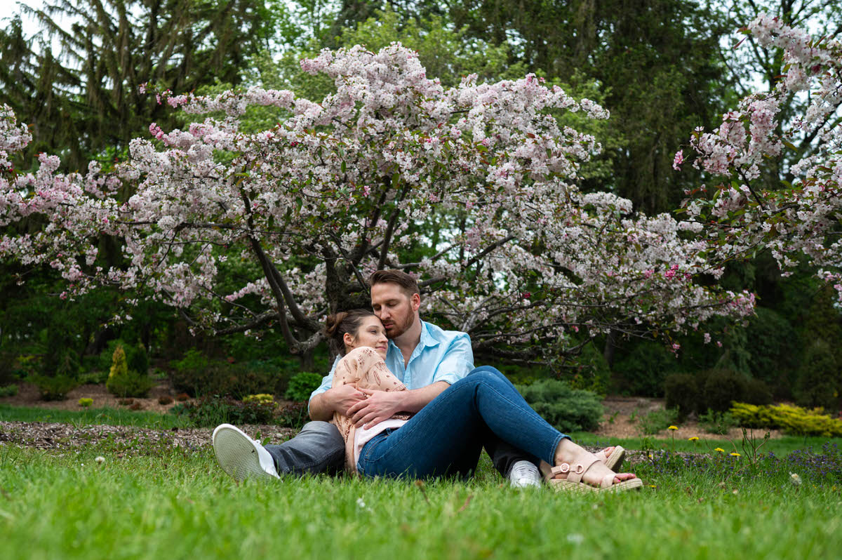 A couple sitting on the ground together in each other's arms in a garden 