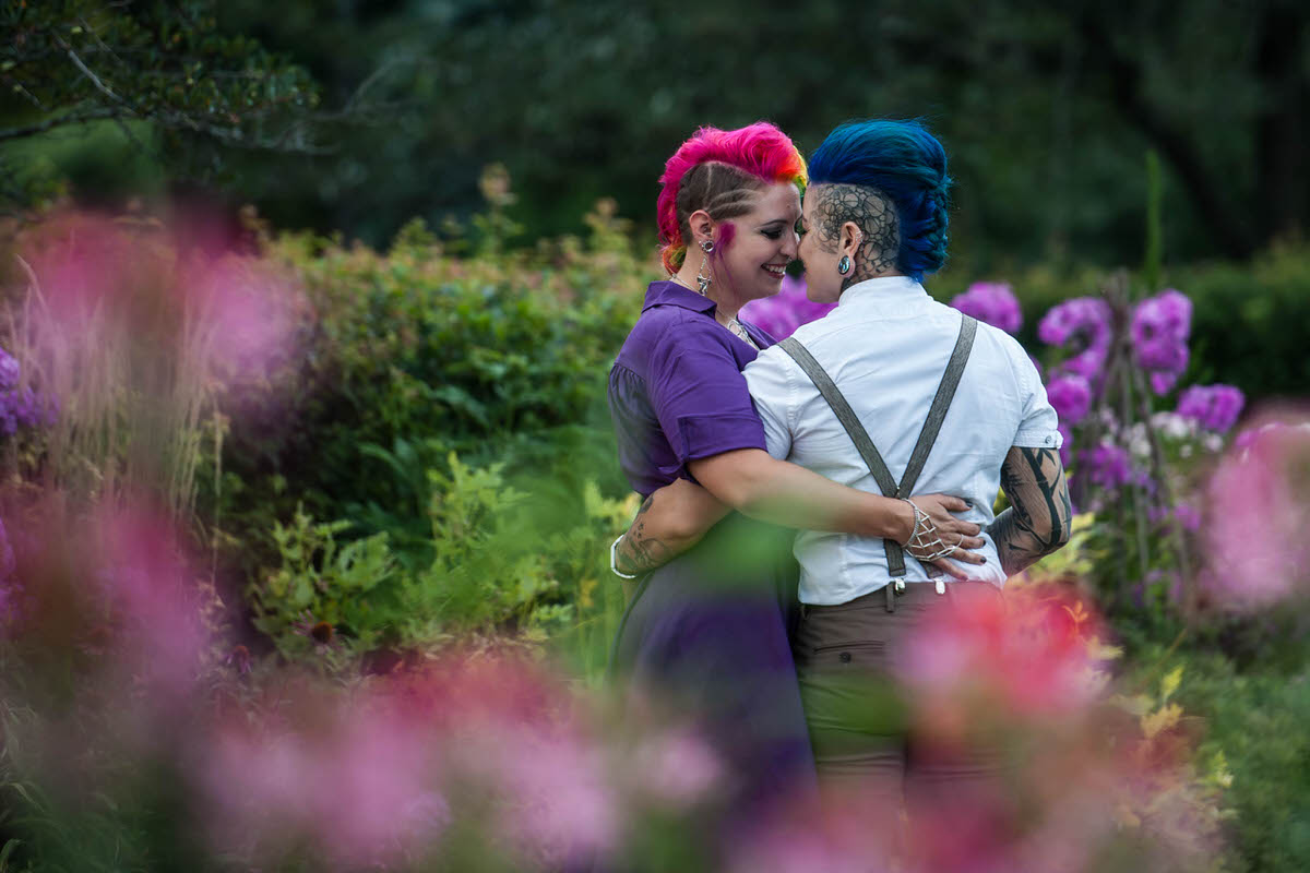 A couple with their arms around each other about to kiss in a garden 