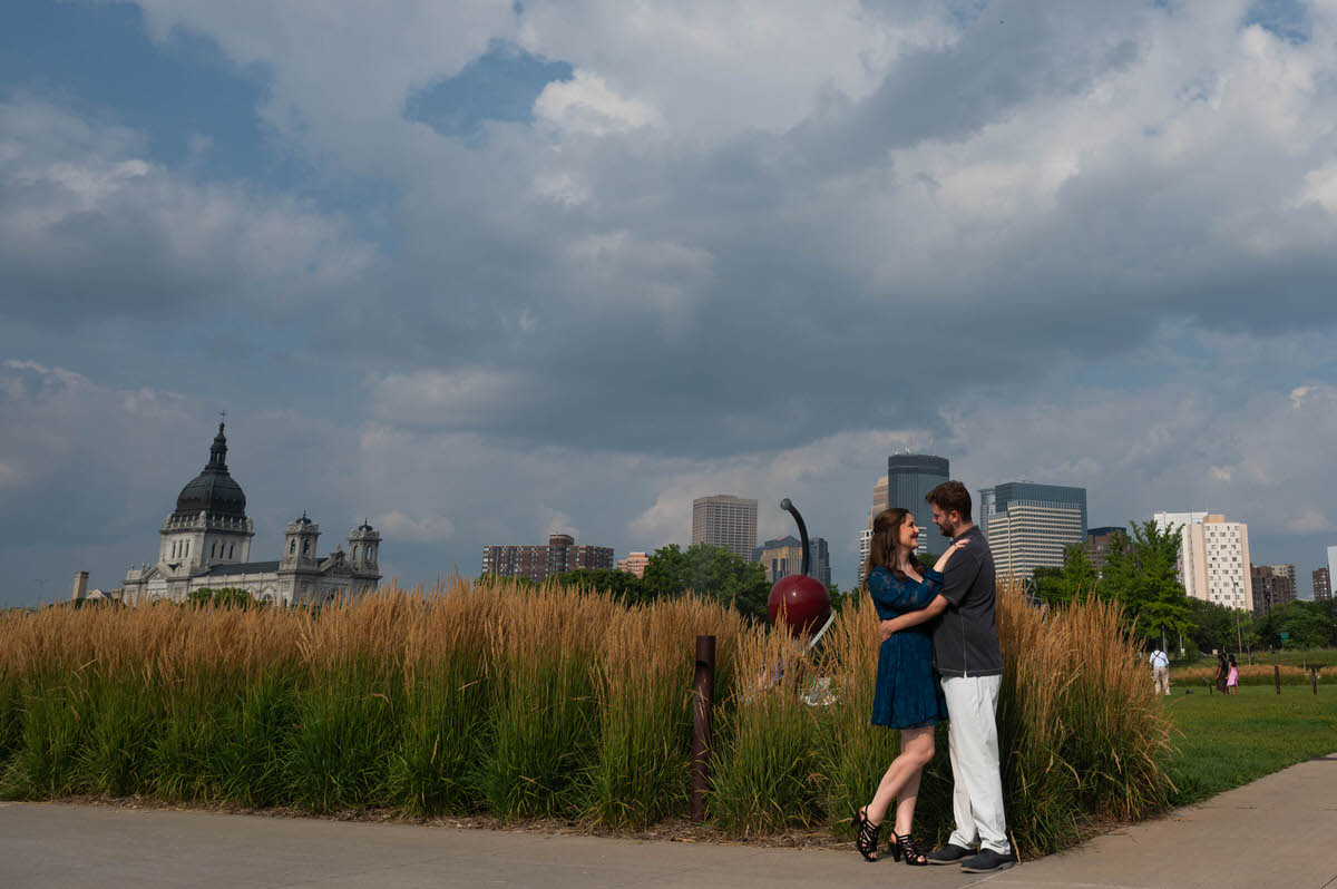 A couple hugging and smiling at the edge of a park 