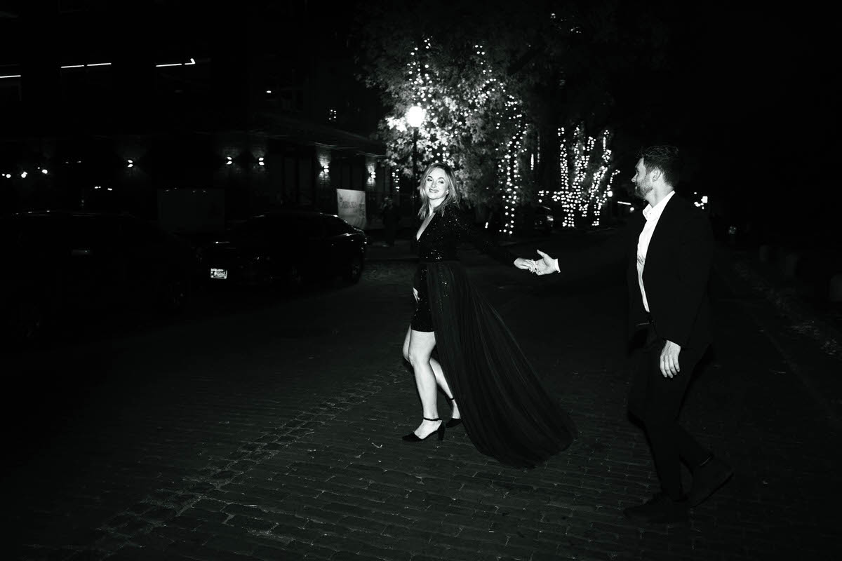 A couple reaching out and holding hands as they walk at night