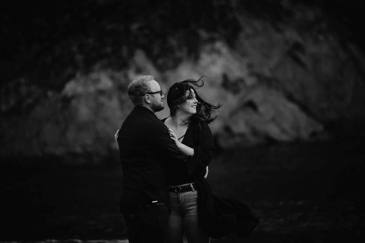 A couple with their arms around each other as they look off into the distance 