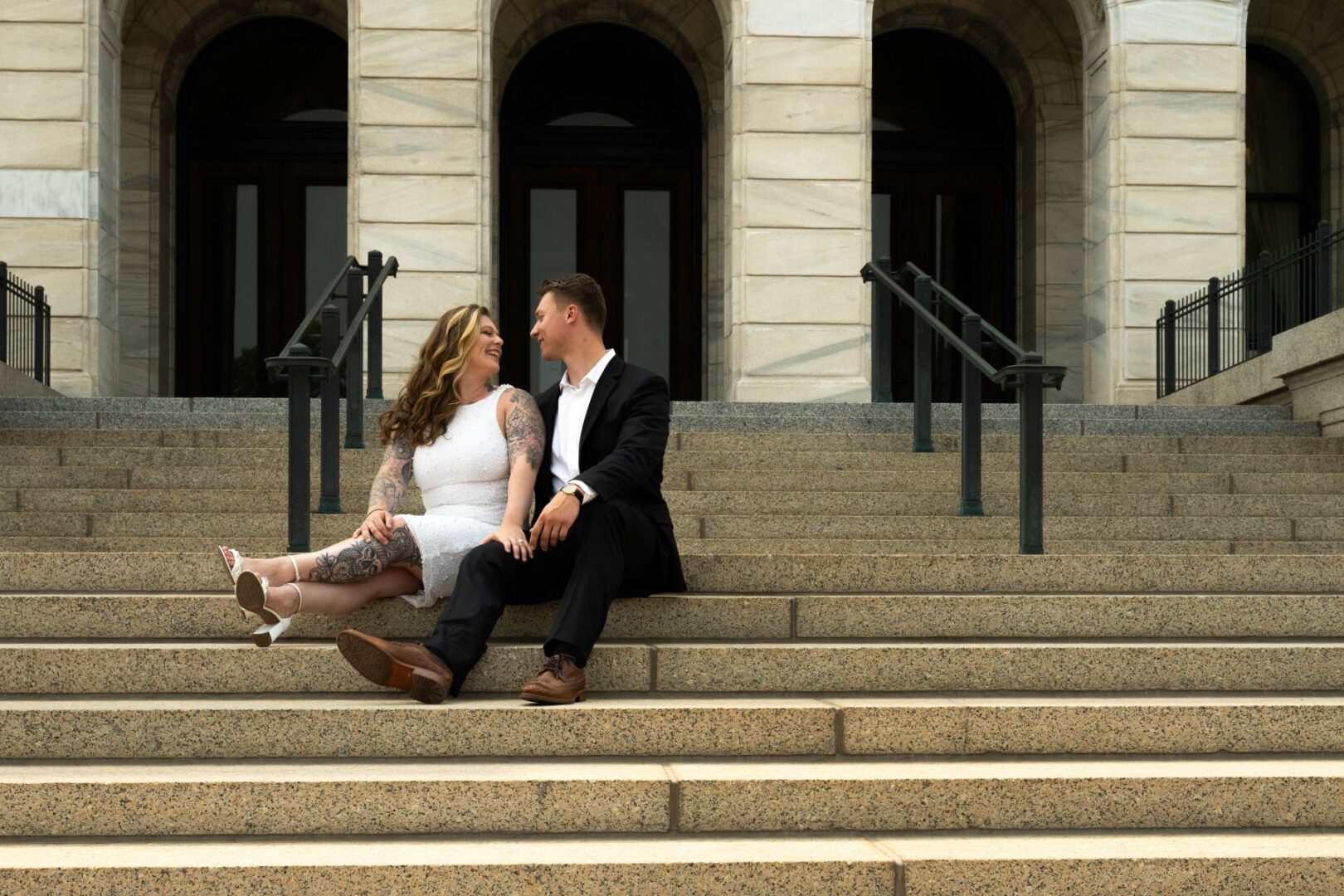 a copule taking engagement photos on the steps of the minnesota state capitol 