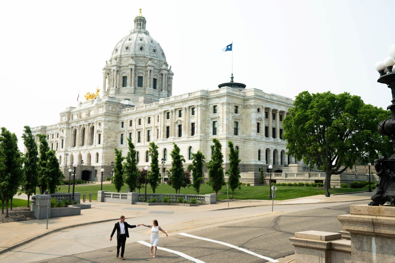 a couple taking engagement photos in front of the minnesota state capitol