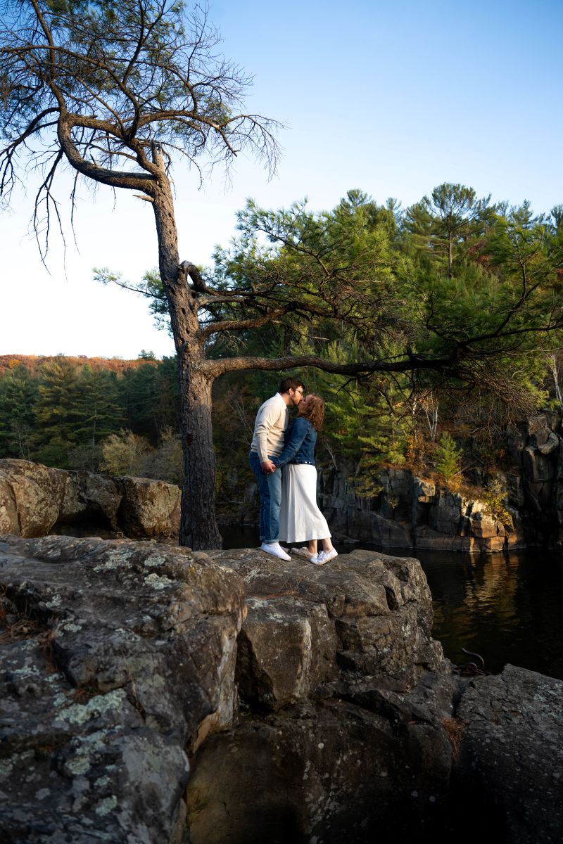 a couple standing on a bluff at taylors falls kissing