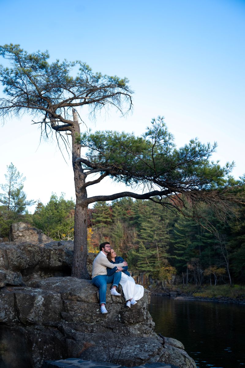 a couple embracing sitting on a rock at taylors falls