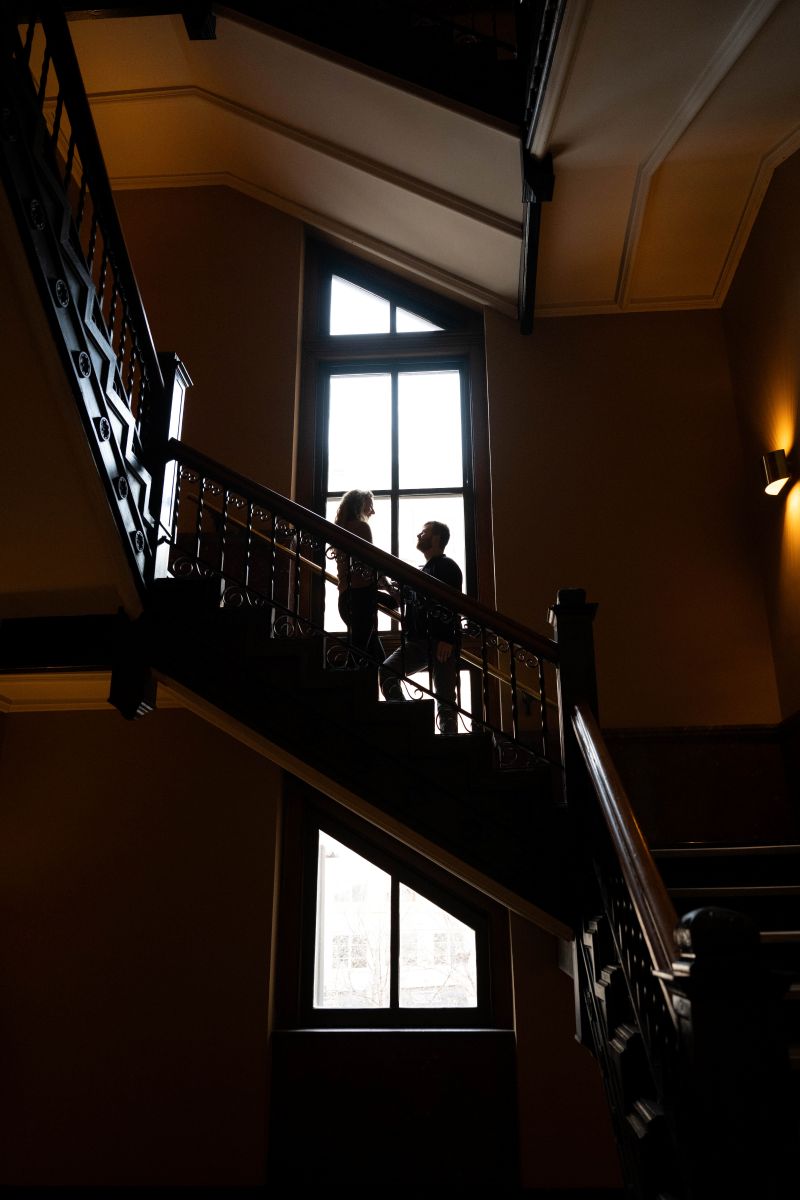 a couple standing on a staircase in landmark center next to a large window