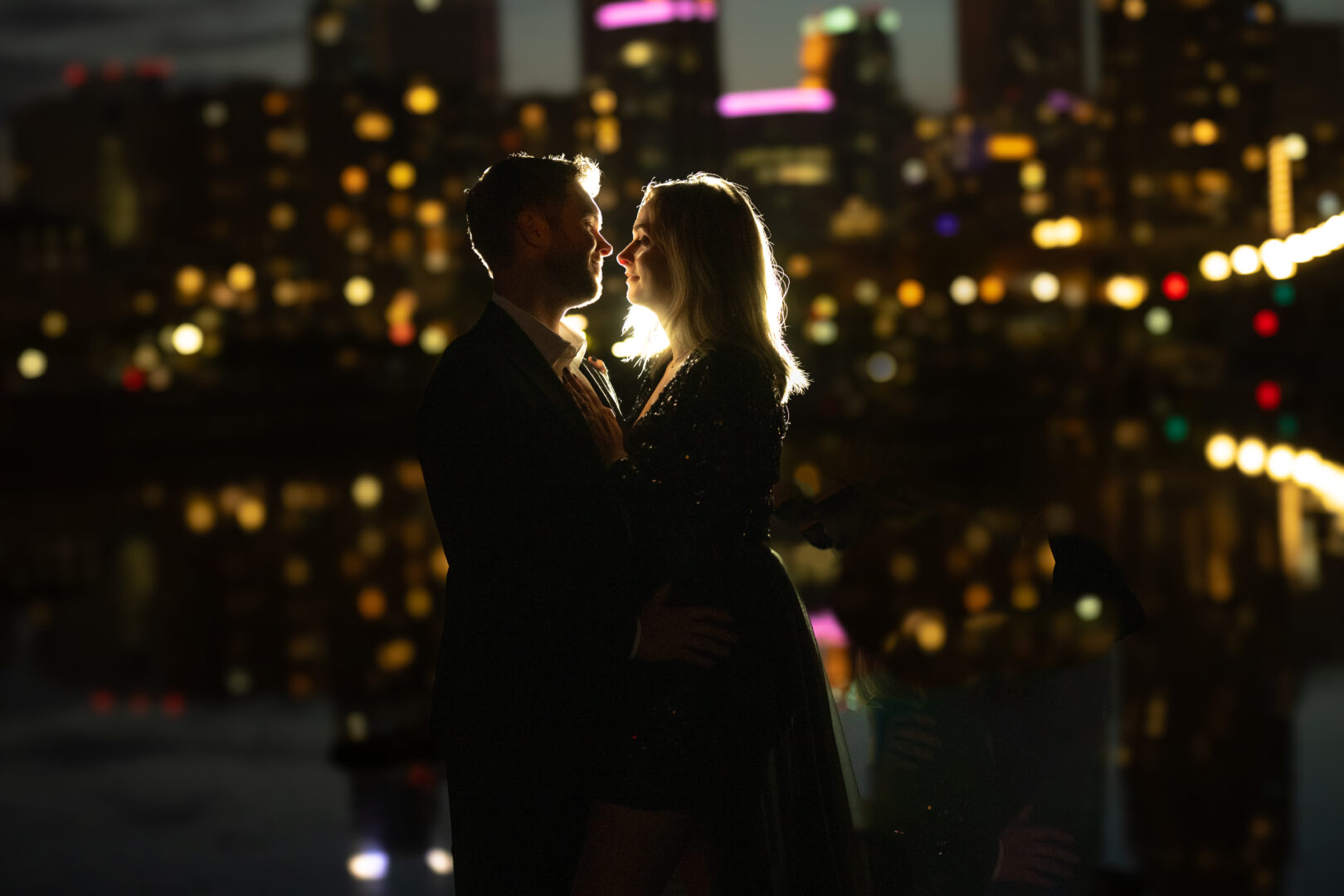 St. Anthony Main evening engagement portrait with lights from Minneapolis skyline.