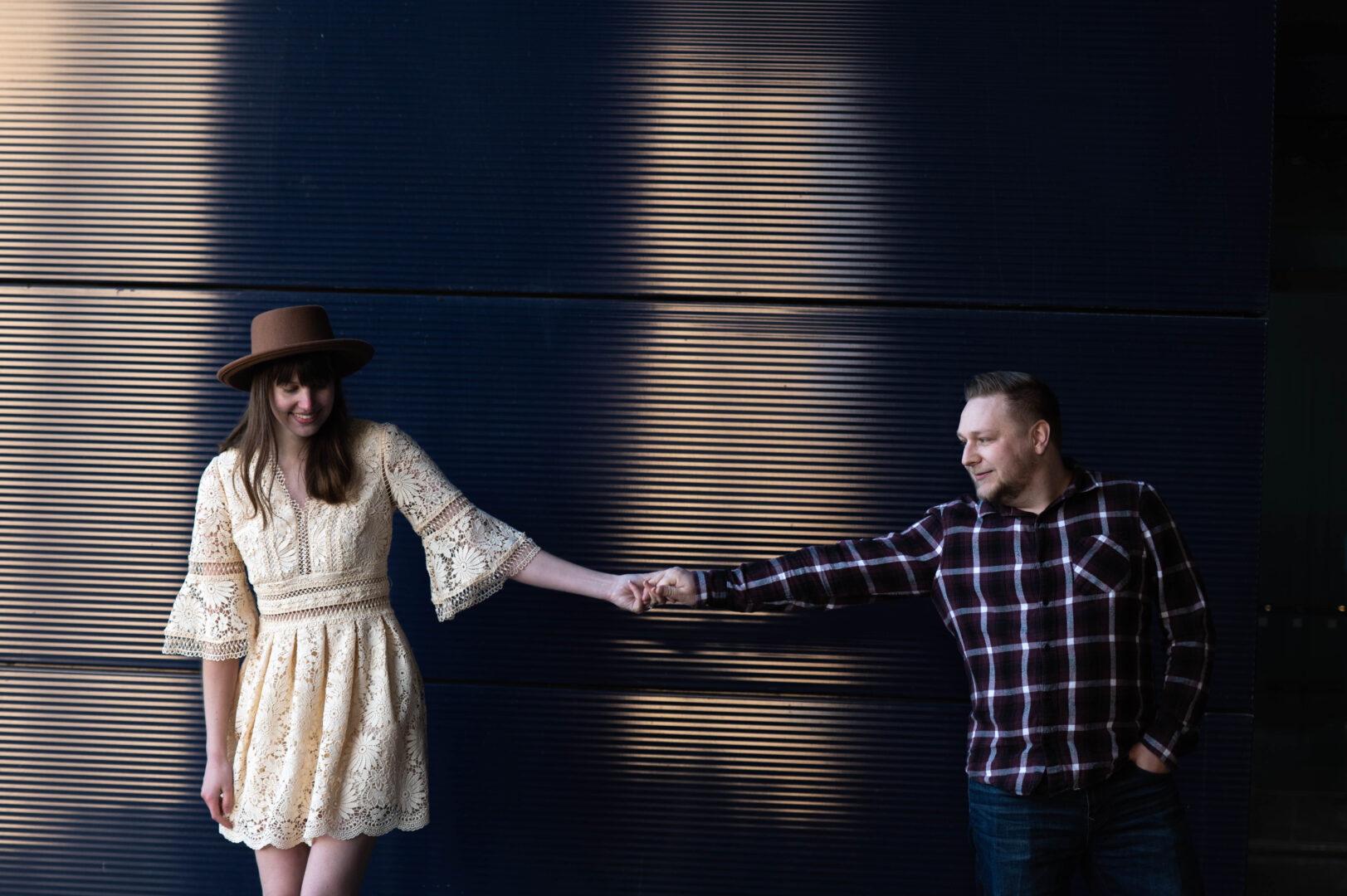 Couple holds hands against the exterior blue wall of the Guthrie Theater in Minneapolis Minnesota