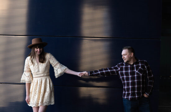 Couple holds hands against the exterior blue wall of the Guthrie Theater in Minneapolis Minnesota