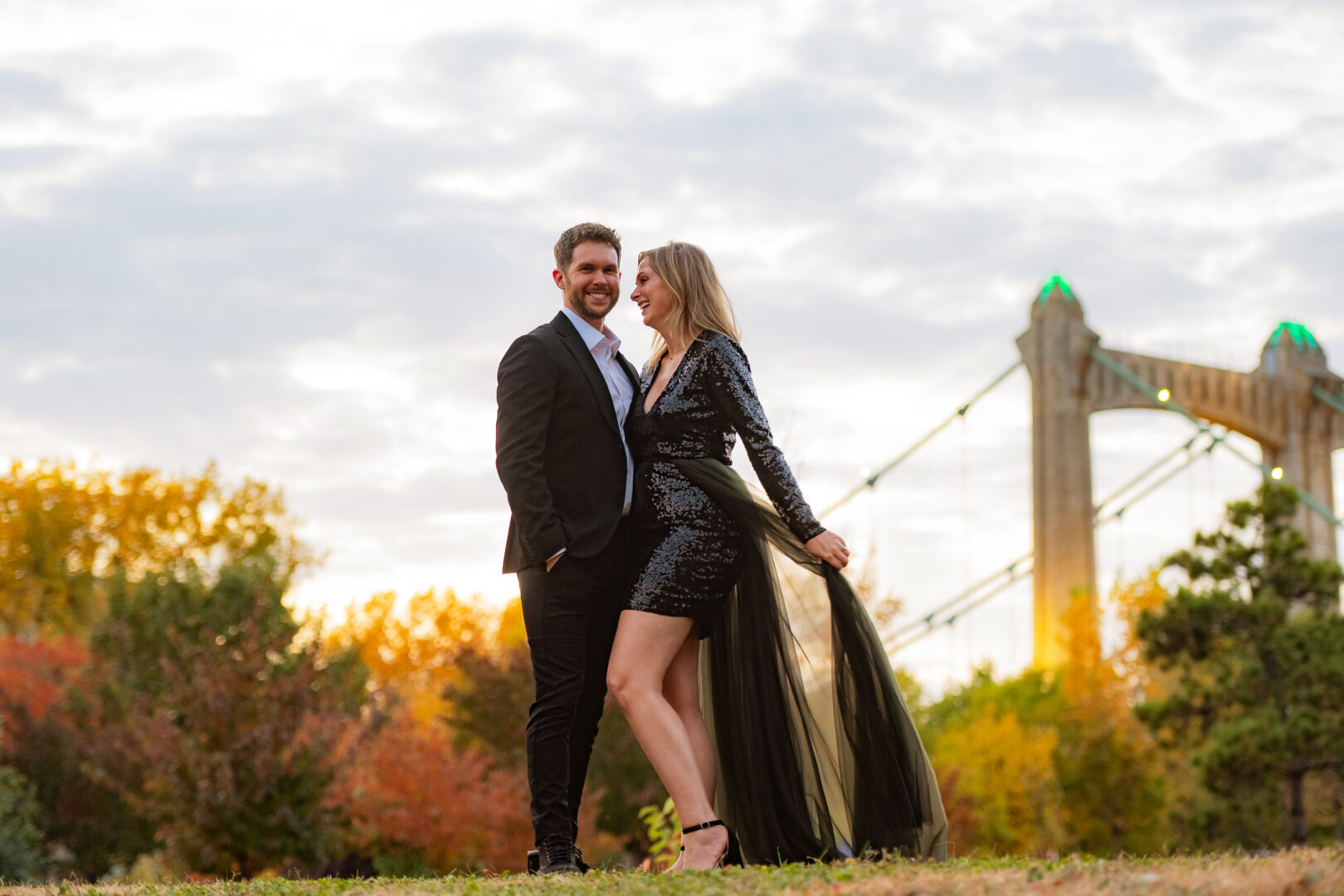 Warm sunlight surrounds couple posing in field at St. Anthony Main.