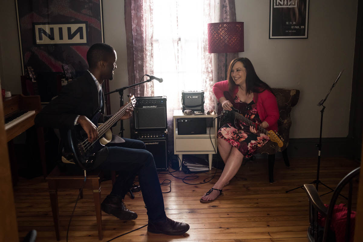 a couple sitting together in their living room playing guitars