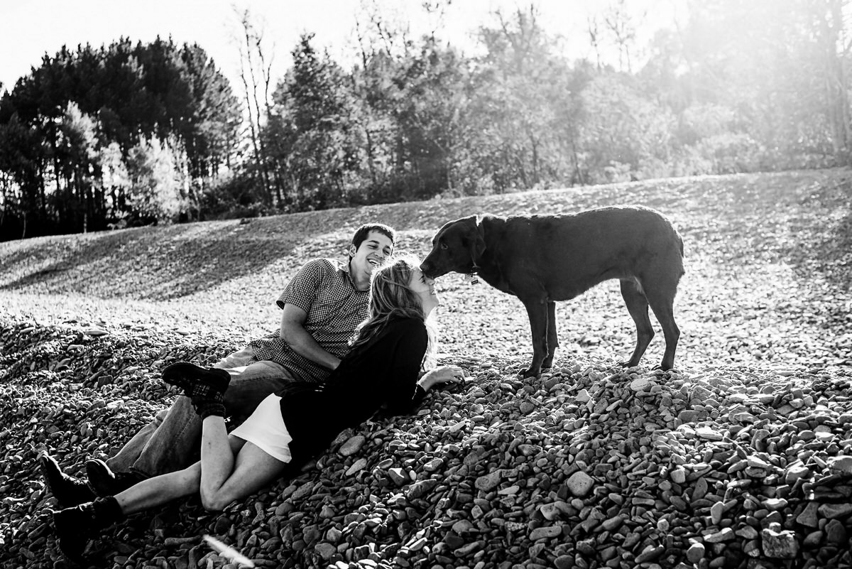 a couple laying on the ground together laughing their dog is sniffing the woman's forehead