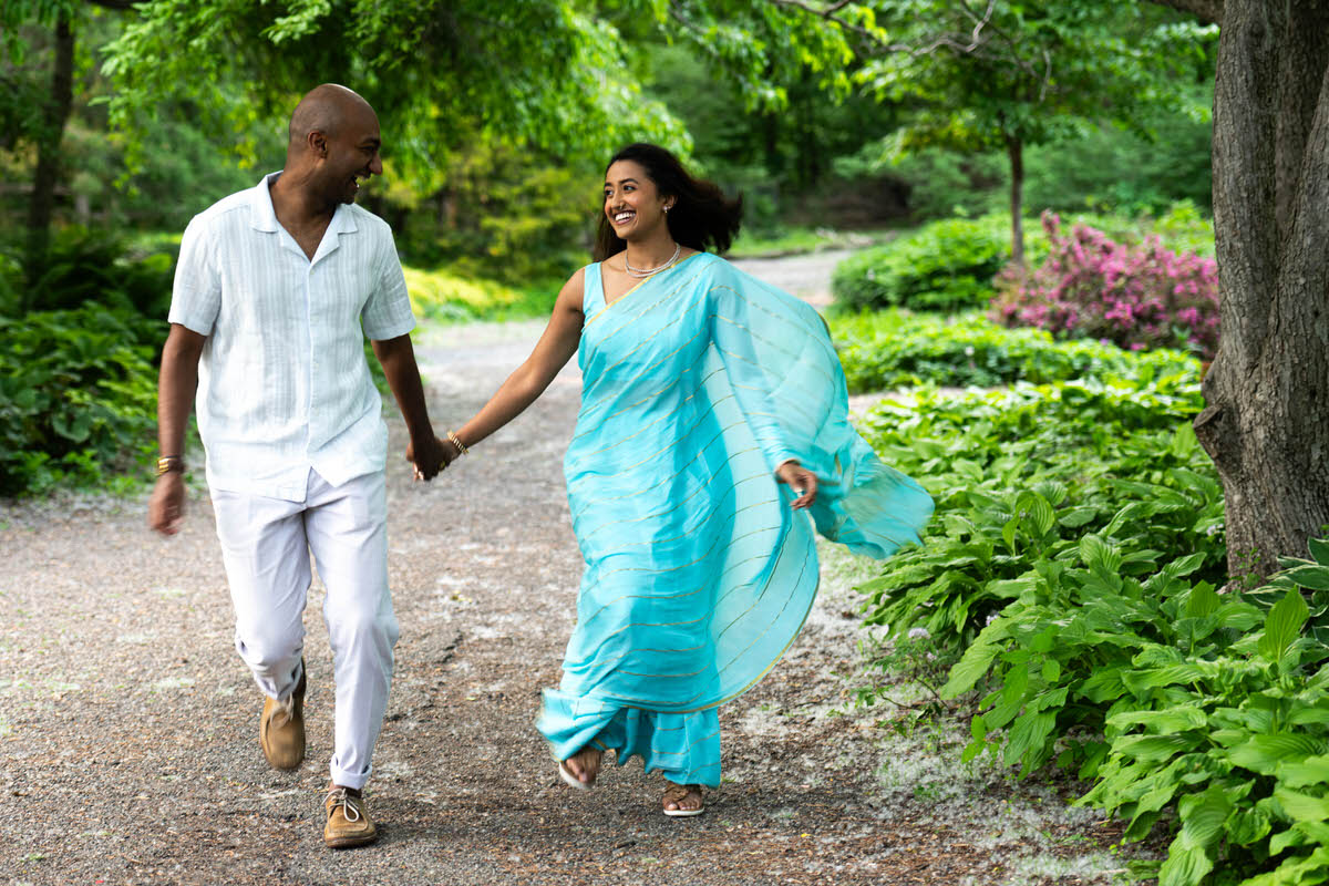a couple holding hands and laughing walking along a paved trail