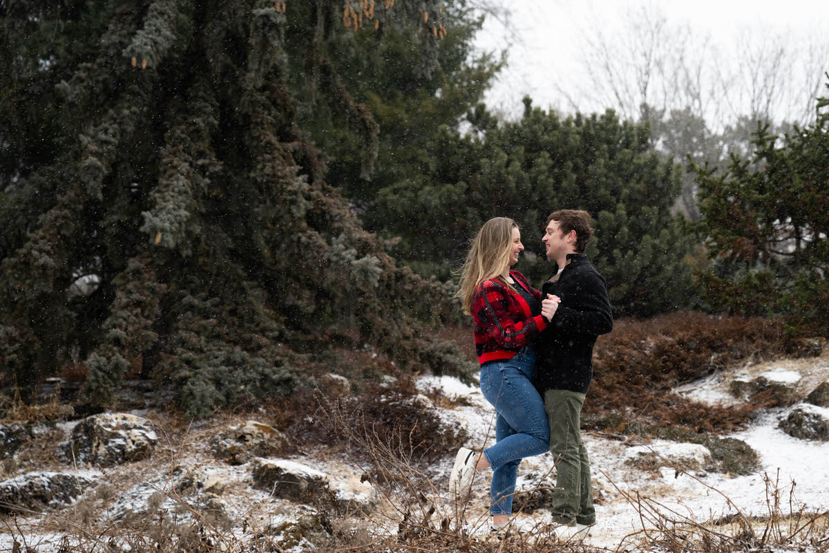 a couple holding hands and smiling at each other in the snow