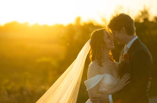 a coupld taking golden hour wedding portraits in a field