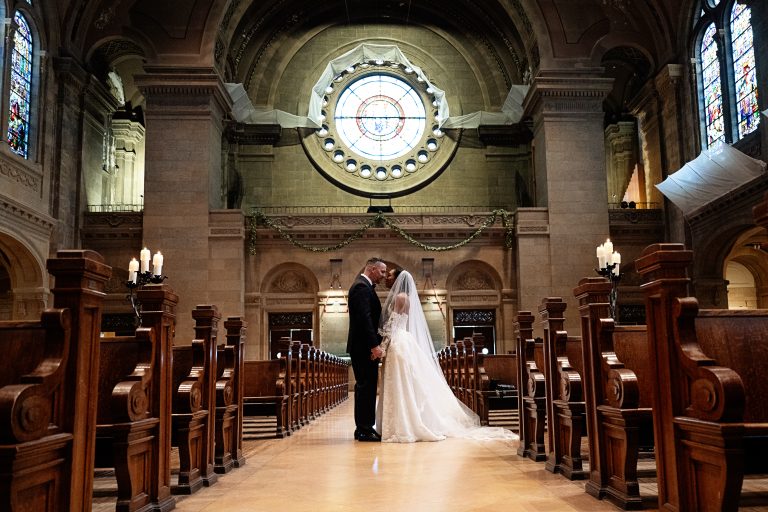 a couple standing in the aisle at The Basilica of Saint Mary taking a wedding portrait
