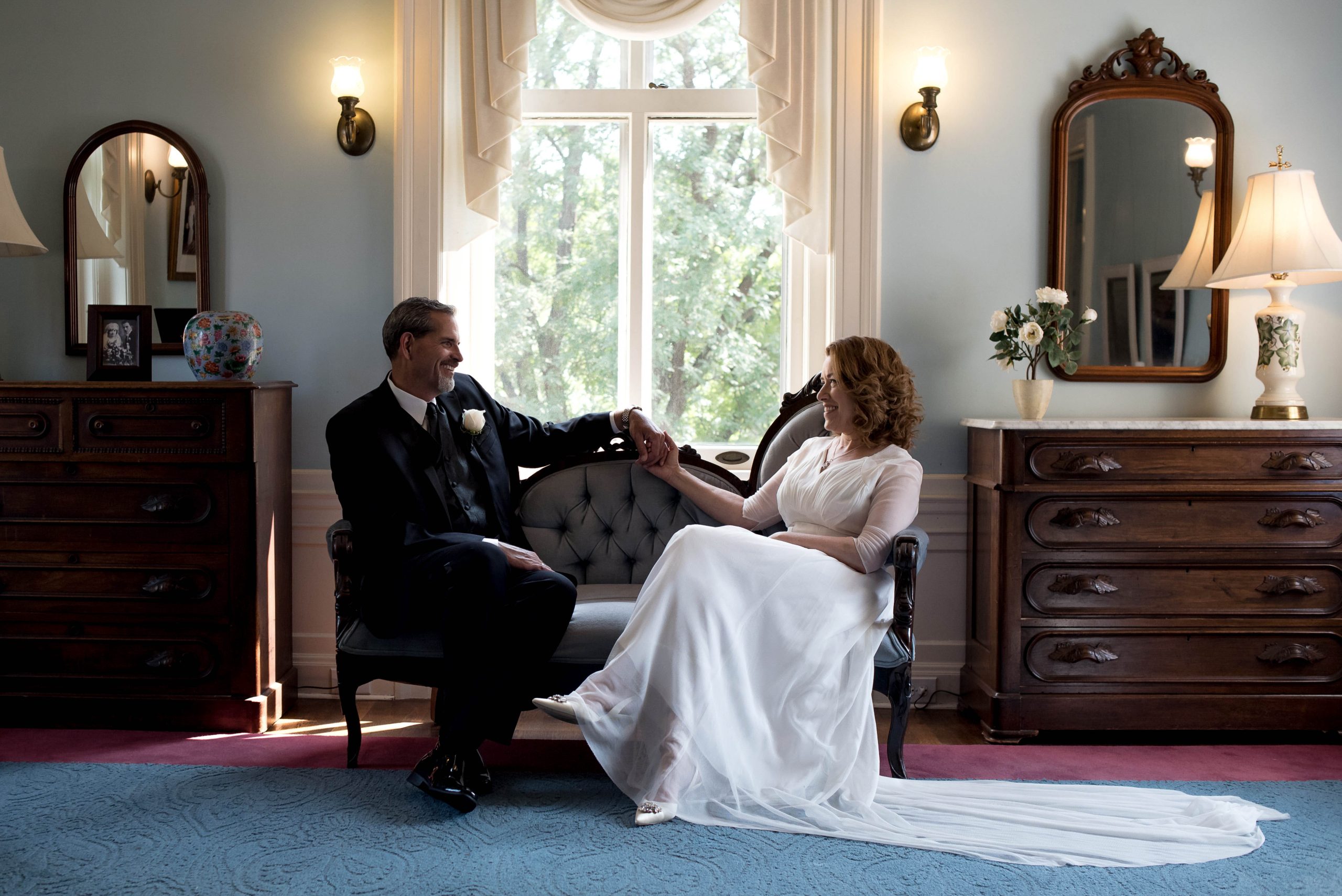 a couple sitting in chairs inside of gale mansion on the day of their wedding