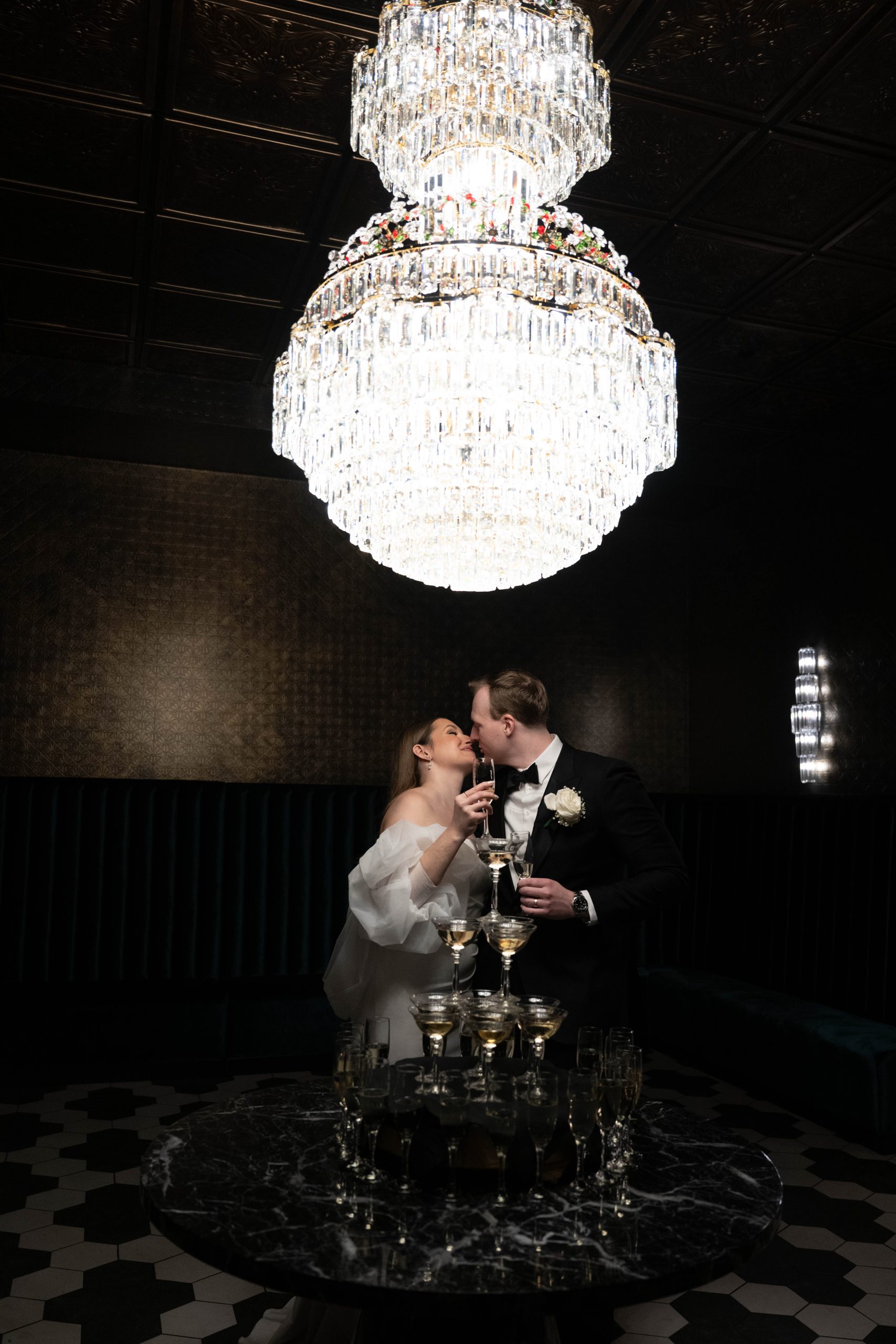 a couple holding up champagne glasses in front of a champagne fountain in Le VENERÉ