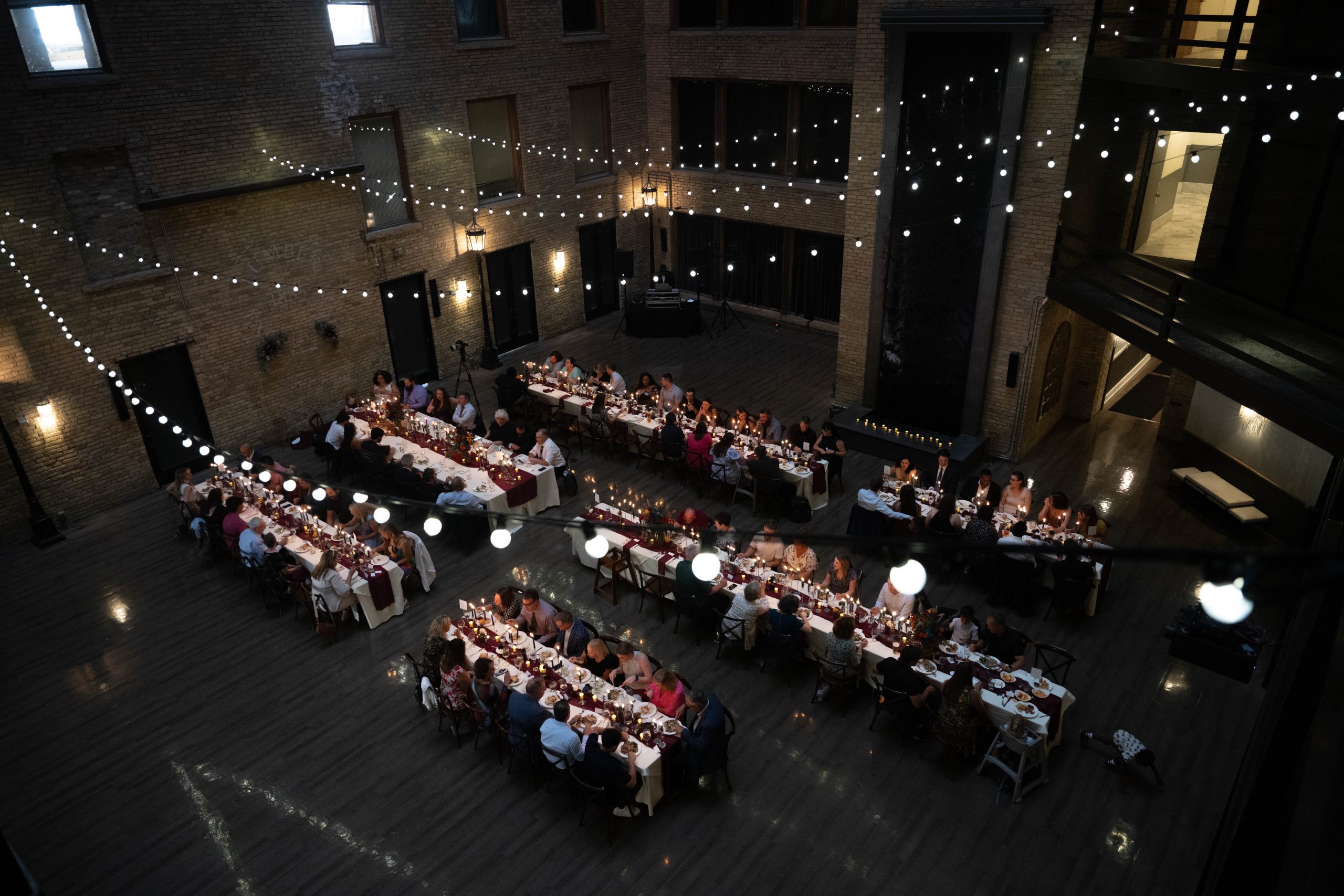 the interior of the Lumber Exchange Event Center set up for a wedding reception with string lights hung overhead