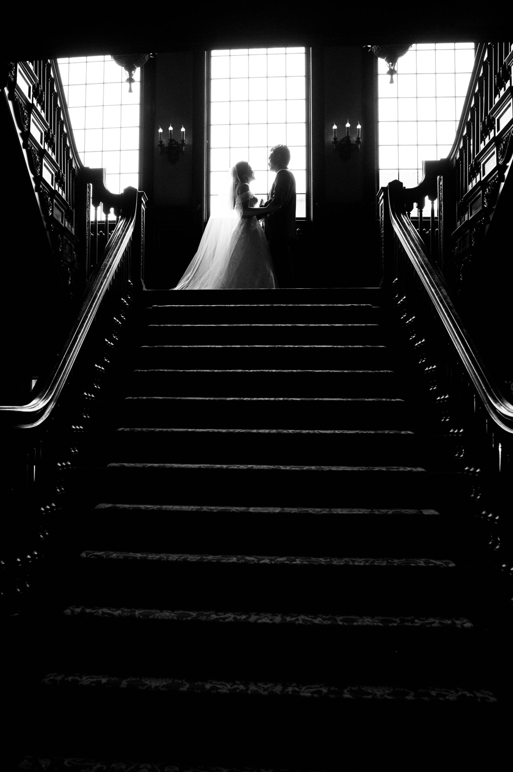 a couple standing at the top of the stairs in semple mansion on the day of their wedding