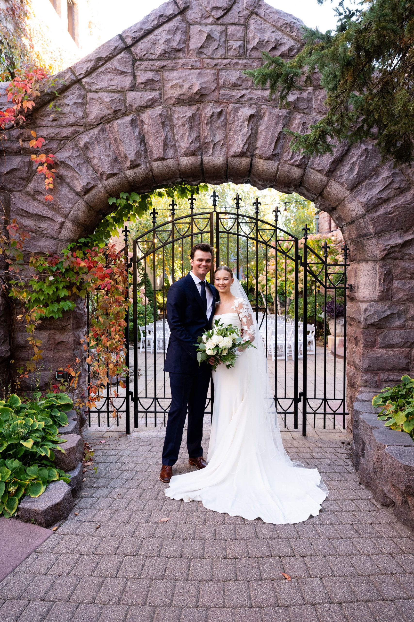 a couple standing in front of the gate on their wedding day at the van dusen mansion