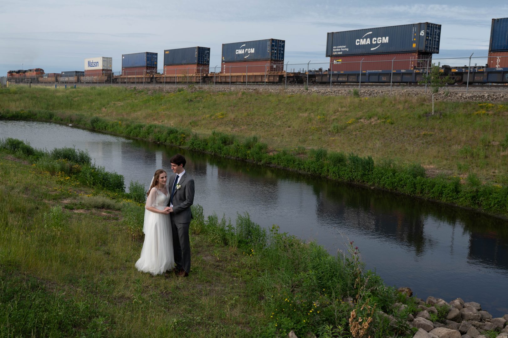 minnesota wedding venues 19 a couple taking wedding portraits next to the water at Northern Stacks Events an industrial-style wedding venue in Fridley, Minnesota